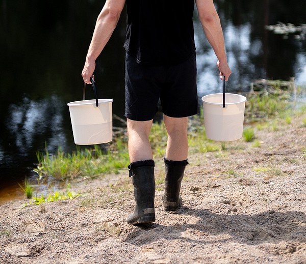 A person carrying water in Orthex buckets